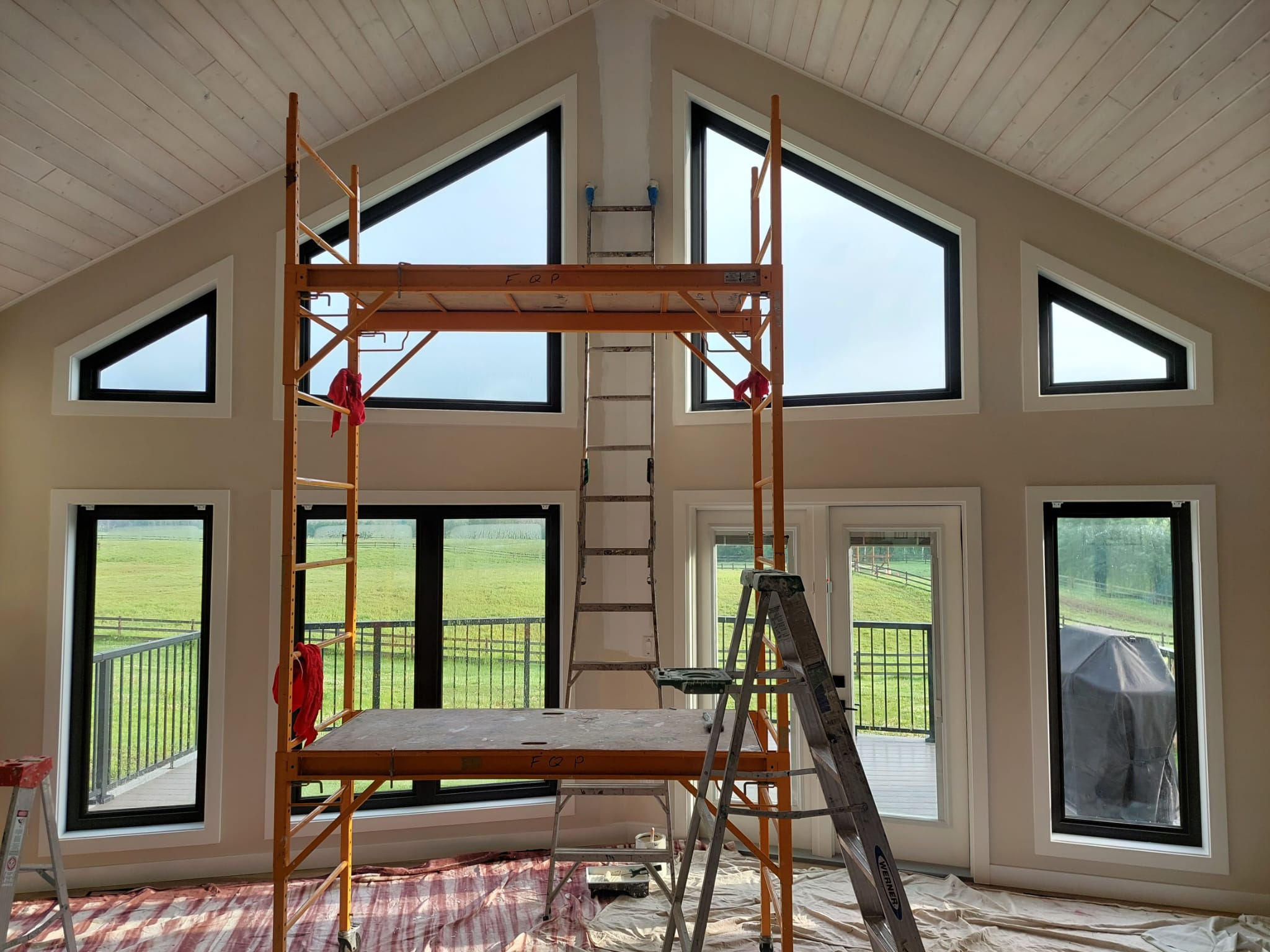 Vaulted great room with whitewashed plank ceiling being painted